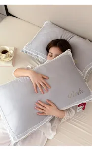 Close-up of lace-edged feather cotton pillow held by a model in bed