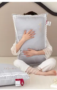 Detailed view of a silver grey pillow with elegant lace border held by a model
