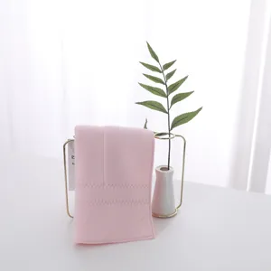 Detailed close-up view of a soft pink latex face towel on a minimalist gold stand