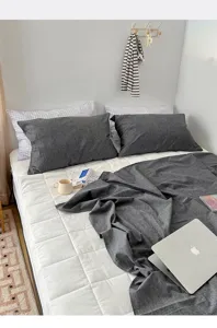Minimalist dark gray washed cotton pillowcases displayed on a cozy white quilted bed