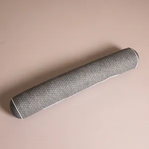 Close-up of grey textured bolster pillow with white piping on beige background