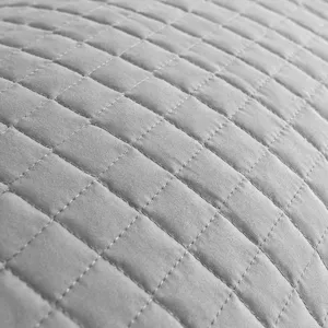 Detailed macro view of grey quilted pillow protector with precise grid stitching texture