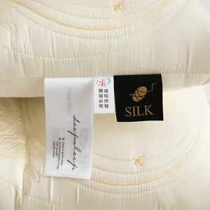 Detailed view of the butterfly embroidery and silk brand tags on a cream latex pillow.