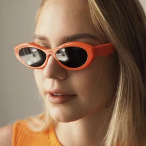 Close-up van een stijlvolle oranje cat-eye zonnebril gedragen door een model nu.