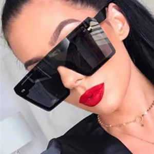 Close-up of oversized square sunglasses with rivet details on model with red lips