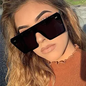 Trendy oversized square black sunglasses with decorative rivets worn by a model in outdoor light