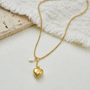 Close-up of gold stainless steel necklace with 3D heart and crescent pearl pendant