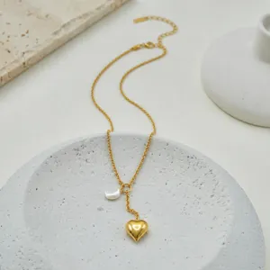 Detail view of a gold heart pendant and crescent moon charm on a delicate chain.