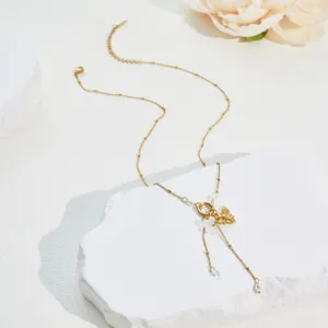 Close-up detail of stainless steel gold bee and flower necklace with pearl tassels