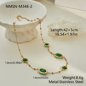 Detail of a gold stainless steel necklace with oval green zircon stones on white prop.
