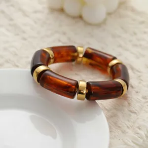 Vue détaillée des tubes en acrylique écaille et des anneaux dorés du bracelet