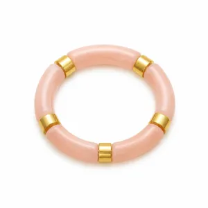 Gros plan sur un bracelet tube en acrylique rose avec des anneaux dorés en métal.