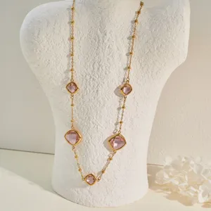 Detailed view of gold stainless steel necklace with faceted pink crystals on white bust.