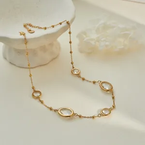 Elegant detail shot of a gold stainless steel necklace with bezel-set oval crystals
