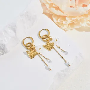 Detailed view of gold stainless steel bee earrings with flower and pearl tassels