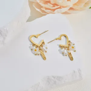 Detailed macro view of gold heart earrings with delicate shell pearls and floral charms