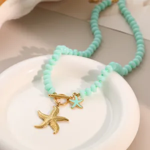 Nahaufnahme einer minzgrünen Perlenkette mit goldenen Seestern-Anhängern