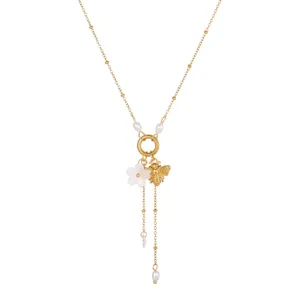 Close-up detail of golden stainless steel bee and flower necklace with elegant pearl tassels