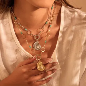 Close-up of gold shell pendant with pearl and turquoise beads on necklace