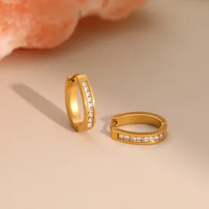 Nahaufnahme von goldenen geometrischen Edelstahl-Ohrringen mit klaren Steinen