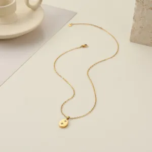 Detalle de un colgante ovalado dorado con grabados de estrellas brillantes.