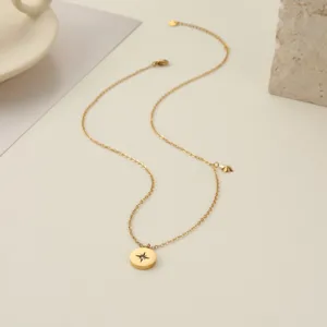 Primer plano de collar de acero dorado con colgante de estrella y piedra central