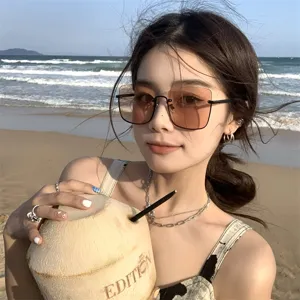 Close-up of woman wearing brown oversized half-frame sunglasses at the beach