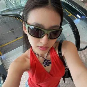 Close-up of a woman wearing olive green Y2K aviator sunglasses in a street style setting