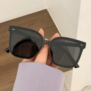 Black oversized sunglasses with rice nail detail held in hand for a detail view.