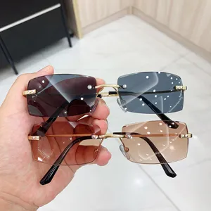 Detail view of two pairs of rimless rectangular sunglasses in dark and brown tints.