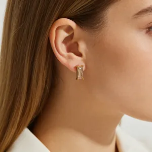 Detail shot of a rectangular champagne zircon earring on a female model's ear