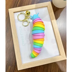 Flexible rainbow slug caterpillar fidget toy keychain displayed in a wooden frame setup
