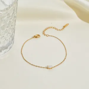 Close-up of a gold stainless steel bracelet with a white gemstone on silk fabric.