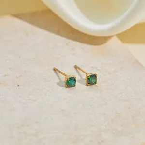 Detailed close-up of gold stud earrings featuring vibrant round green cubic zirconia stones