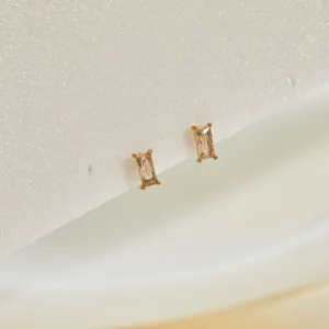 Close-up of minimalist stainless steel stud earrings with rectangular champagne zircon stones.