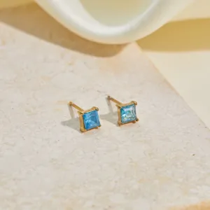 Close-up of gold-plated stainless steel stud earrings with square-cut blue zircon.