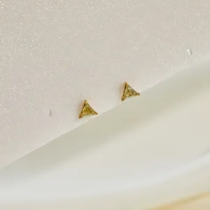 Close-up of triangle-shaped gold stainless steel earrings with yellow zircon gemstones