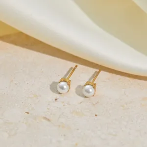 Detail of elegant gold-plated stainless steel stud earrings with white round pearls