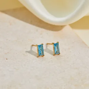 Detail view of rectangular blue zircon stud earrings in gold stainless steel setting.