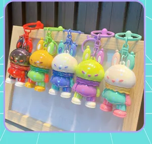 Colorful pearlescent rabbit keychains in five color combinations hanging on a wood frame