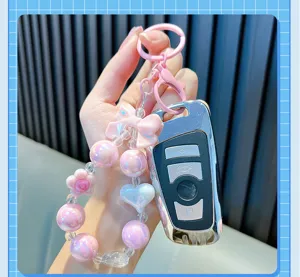 Close-up of pink iridescent beaded keychain with heart and flower charms