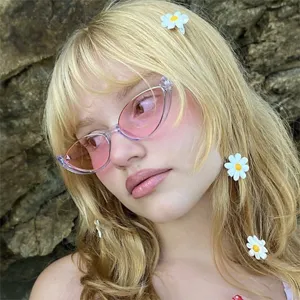 Detailopname van een retro cat-eye zonnebril met roze glazen gedragen door model.