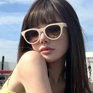 Primer plano de una modelo con gafas de sol cat-eye retro de color crema al sol