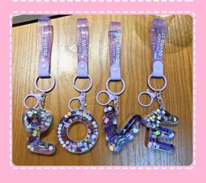 Detailed view of four purple liquid quicksand keychains spelling out LOVE with sequins