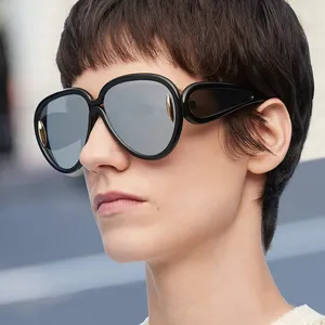 Close-up of model wearing futuristic large frame black sunglasses with reflective lenses.