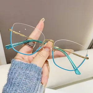 Detail van groenblauw cat-eye brilmontuur met goudkleurige veren en heldere glazen.