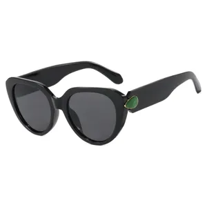 Stijlvolle dames zonnebril cat-eye met groen edelsteen detail en groot zwart montuur