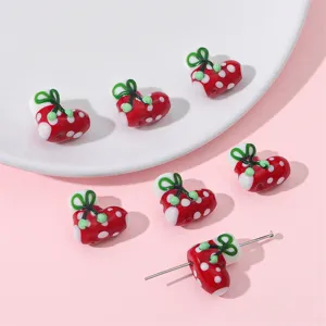 Detailed view of red polka dot heart beads for DIY jewelry making on a pink background