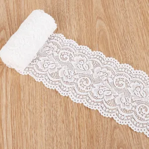 Detailansicht von weißer elastischer Spitzenborte mit Blumenmuster auf Holzoberfläche