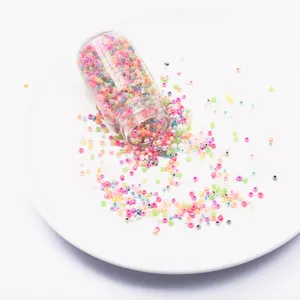 Macro view of 2mm colorful glass seed beads spilling from a clear bottle on a white plate